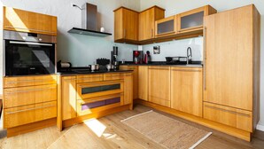 Una cocina moderna con armarios de madera, horno empotrado y campana extractora de acero inoxidable.