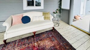 A white sofa with patterned cushions, a decorative rug, and a window with a view. - Bonanza Blast in SW Boise (Boise)