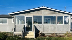 A single-story mobile home with a covered porch, a sliding glass door entrance, and a small front yard. - Bonanza Blast in SW Boise (Boise)