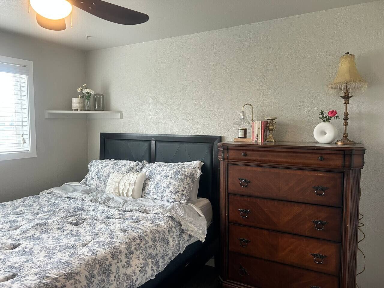 Une chambre à coucher comprenant un lit, une commode et des étagères décorées d’objets d’ornement.