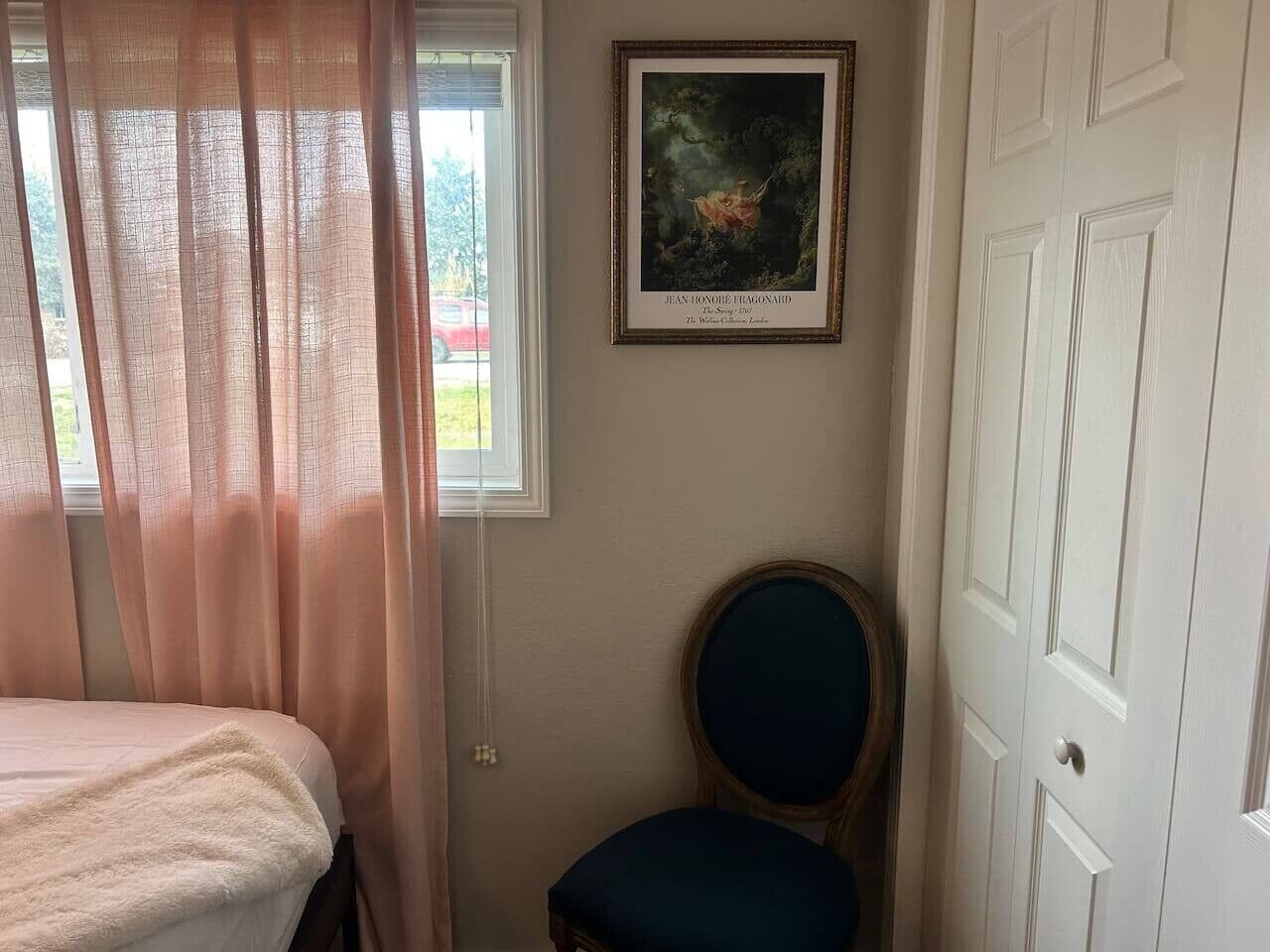 Une chambre à coucher avec un lit, une chaise, une fenêtre avec des rideaux et une porte.