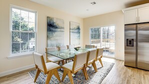 A dining area with a glass table and chairs, large windows, and a stainless steel refrigerator. - Walk to Keansburg Beach! Family Home w/ Pool (Keansburg)