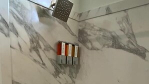 Ein Badezimmer mit Marmorwand, einer Badewanne und einer Duschbrause.