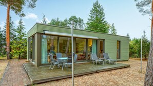 Uma cabana moderna com varanda, portas de vidro e área de estar externa.