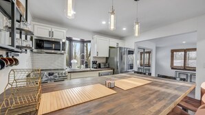 A modern kitchen with white cabinets, stainless steel appliances, and a wooden island.