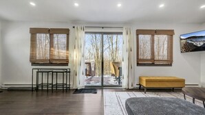 A modern interior with a large sliding glass door leading to a snowy outdoor area, a bench, a table, and a framed picture on the wall.
