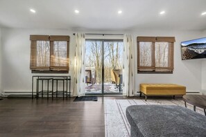 A modern interior with a large sliding glass door leading to a snowy outdoor area, a bench, a table, and a framed picture on the wall.