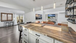 A modern kitchen with a central island, pendant lighting, and a dining area with a fireplace.