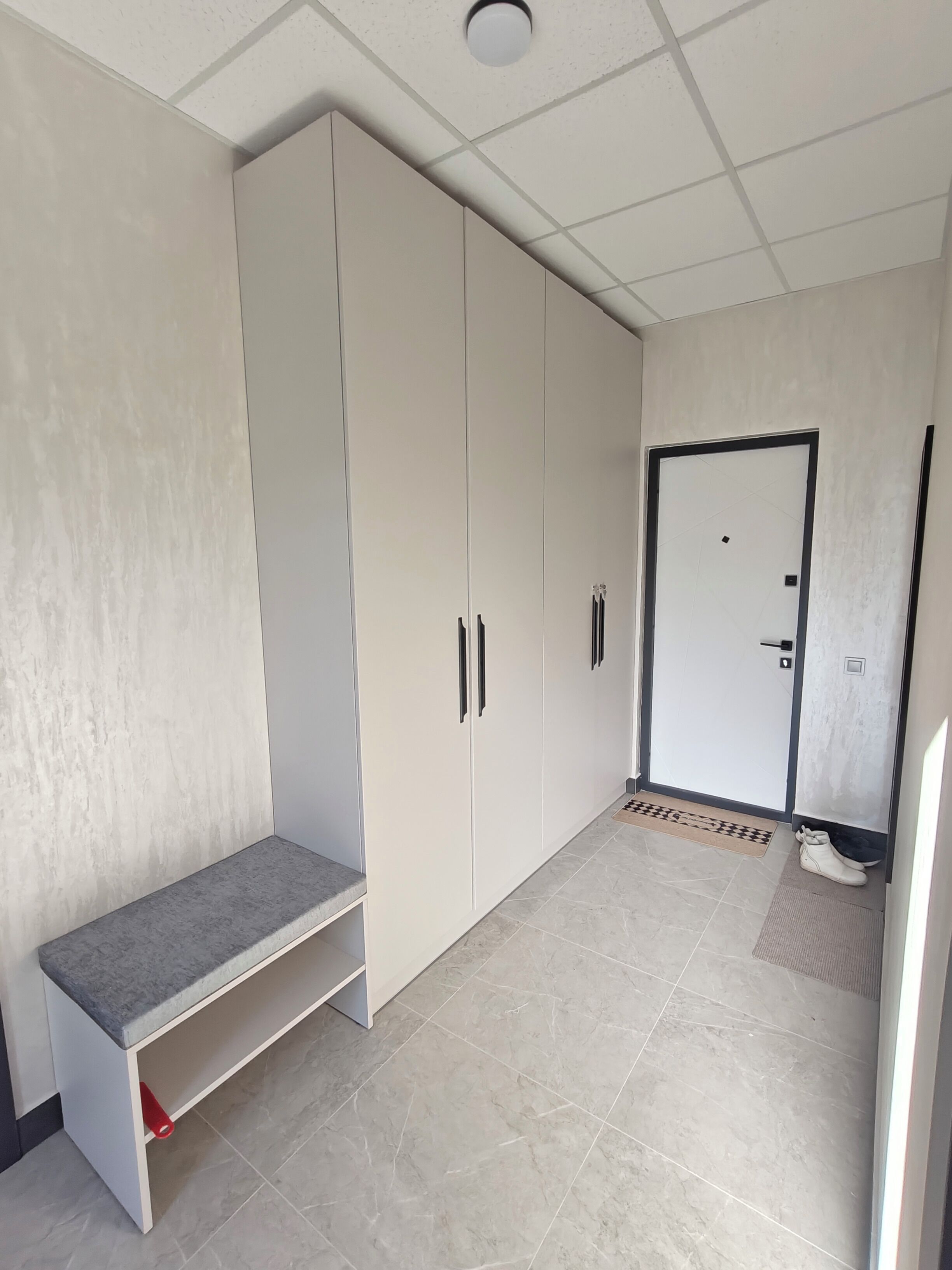 A room with a large wardrobe, a bench, and a door.