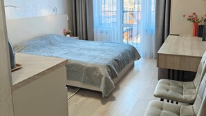 Une chambre d’hôtel moderne équipée d’un lit, d’un bureau, d’une chaise et d’un balcon avec vue.