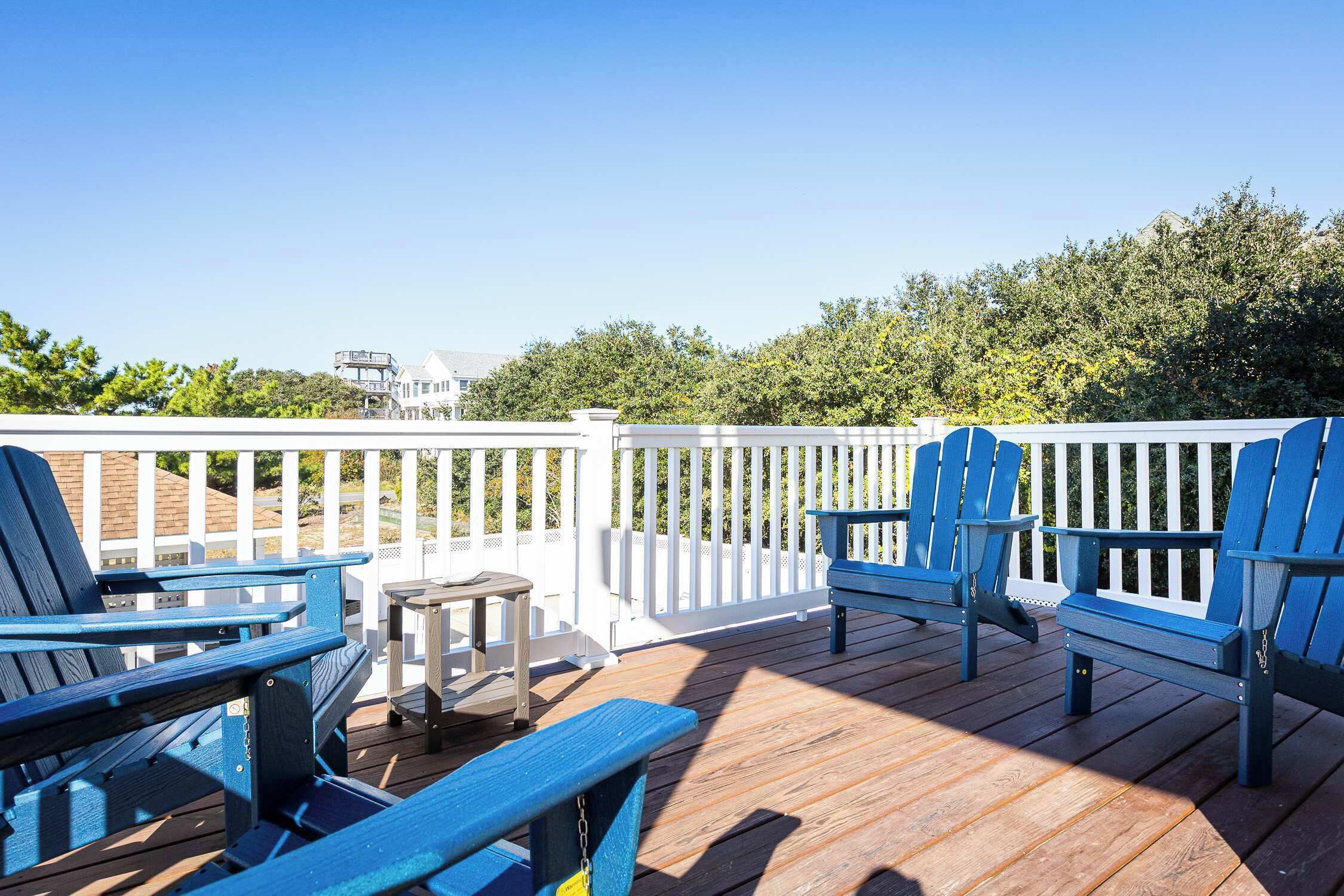 Une terrasse en bois avec des chaises Adirondack bleues et une petite table.