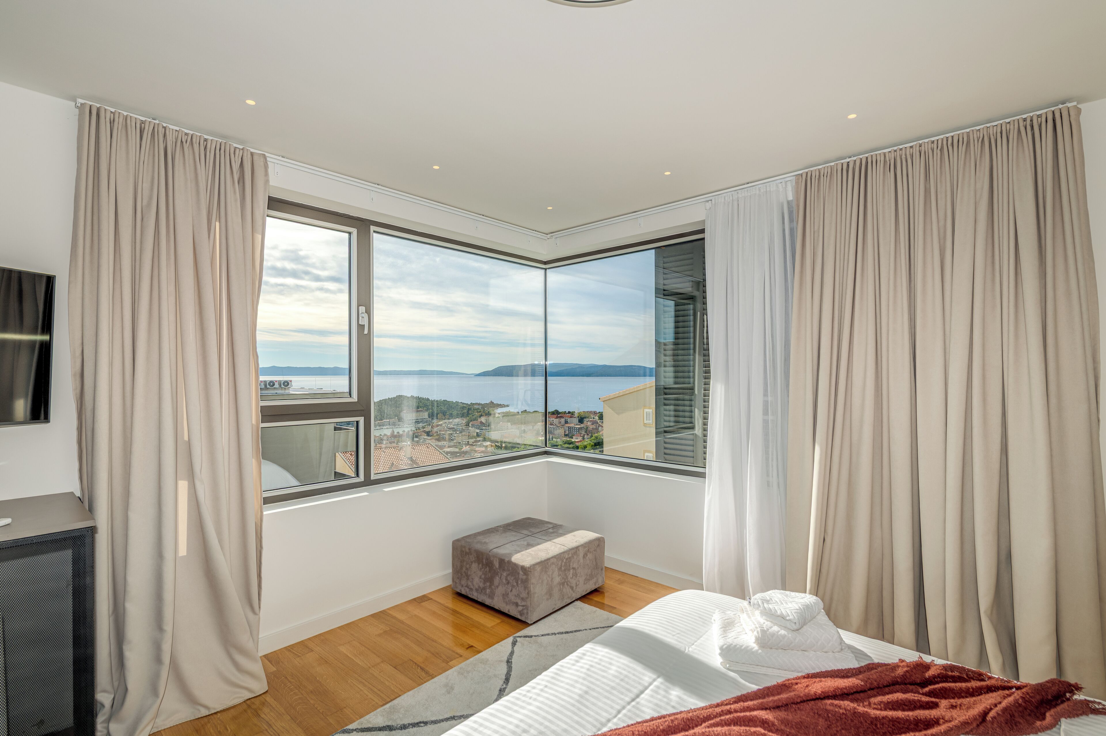 Una habitación de hotel moderna con un amplio ventanal que ofrece una vista panorámica del mar y el paisaje urbano.