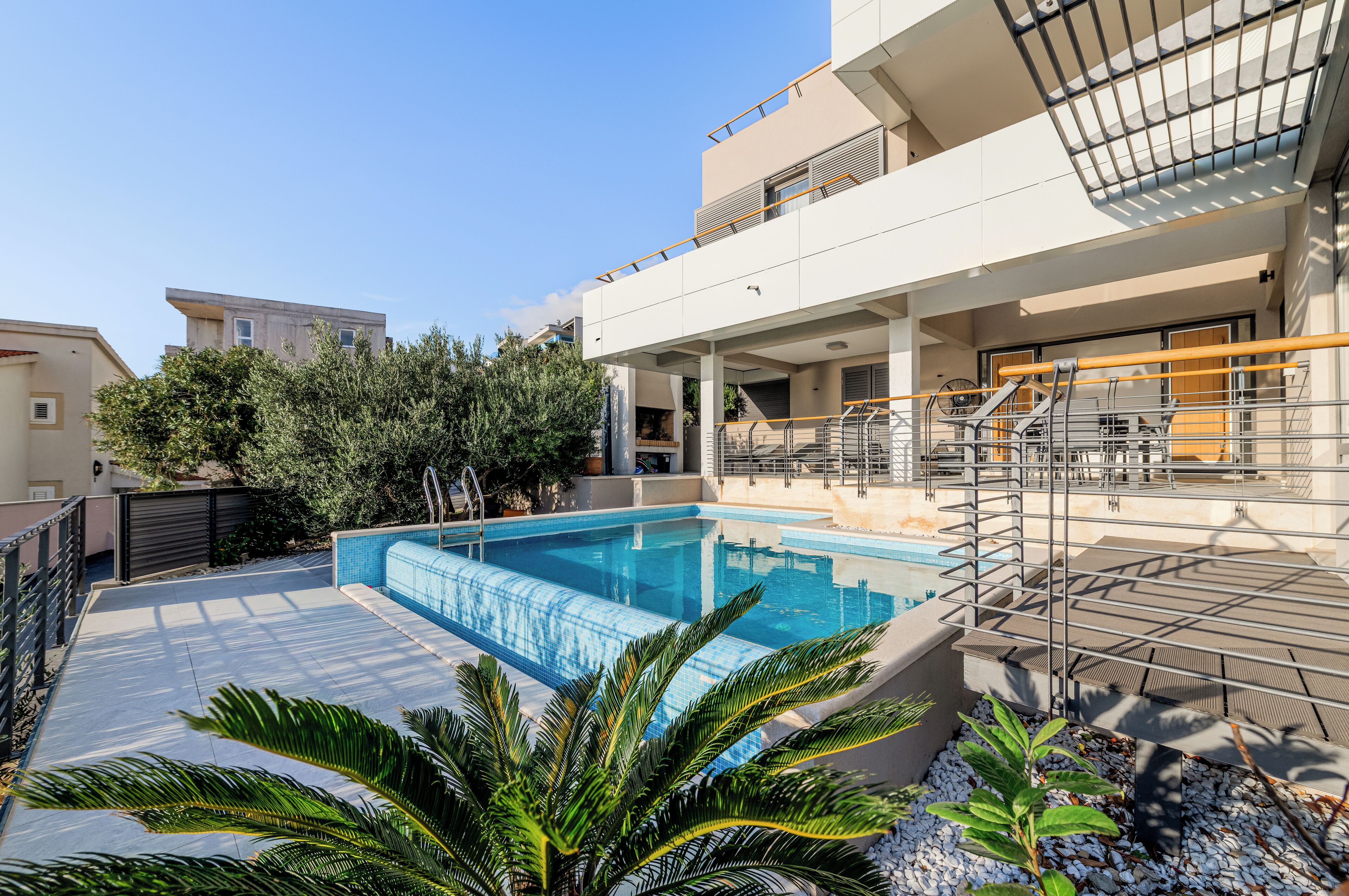 Un edificio residencial moderno con piscina, zona de estar al aire libre y balcón.