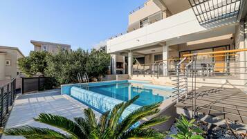 Un edificio residencial moderno con piscina, zona de estar al aire libre y balcón.