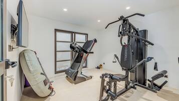 A gym with a treadmill, weight machine, and a large mirror.