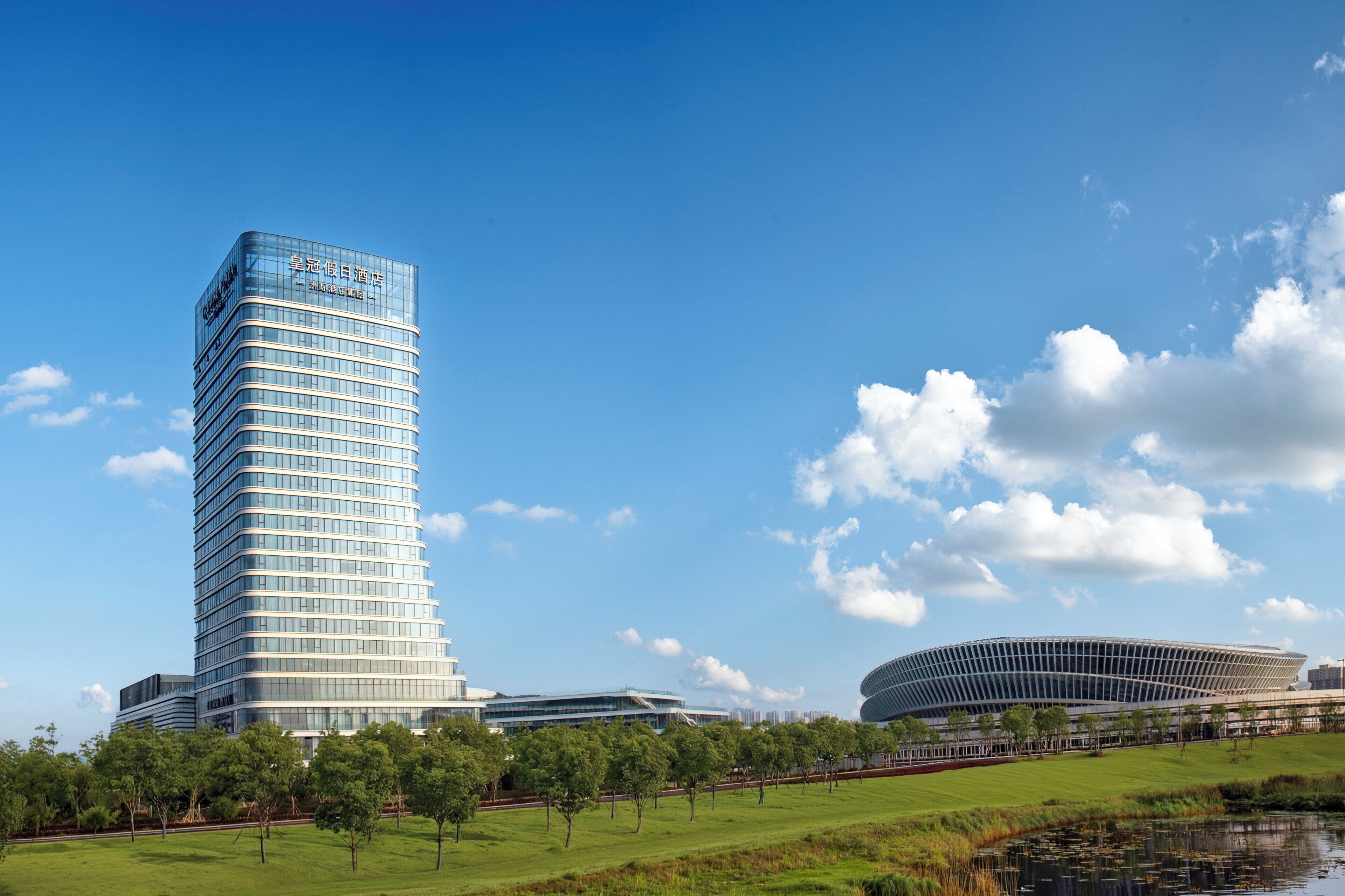 A modern hotel with a curved facade, a large glass window, and a sign in a foreign language.