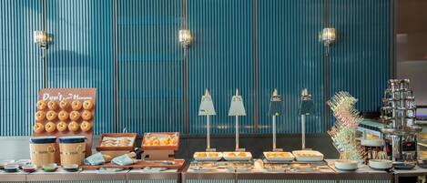 A buffet setup with various food items, a sign with a message, and a decorative plant.