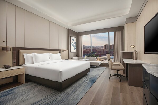 A modern hotel room with a large bed, a desk, a chair, and a TV. - Crowne Plaza Linyi Olympic Sports Centre by IHG (Linyi)