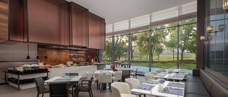 Un comedor moderno con ventanas amplias, una cocina con armarios de cobre y vistas al exterior.