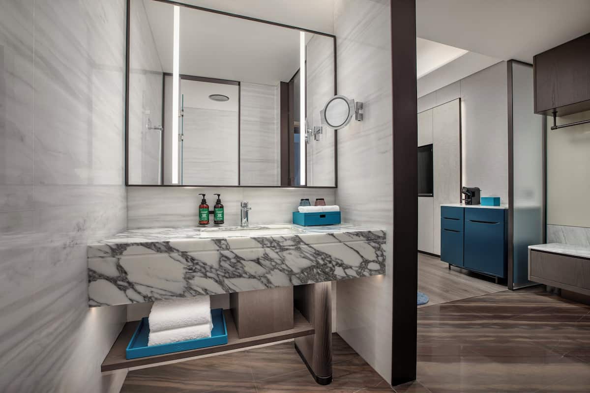 A modern bathroom with a marble sink, a large mirror, and a blue cabinet.