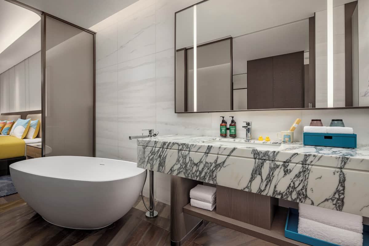 A modern bathroom with a freestanding bathtub, a large mirror, and a marble countertop.