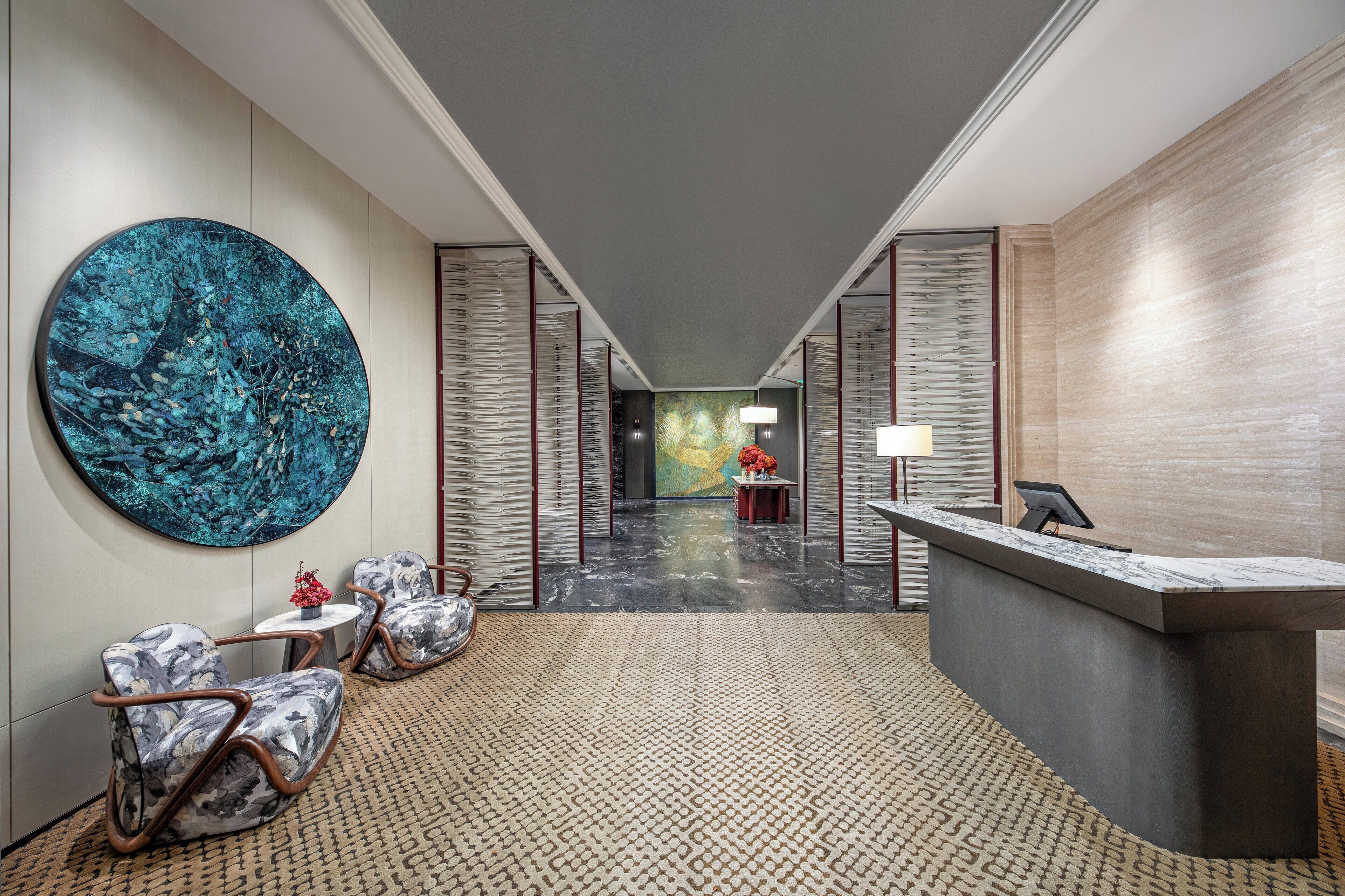 A modern lobby with a reception desk, seating area, and a large abstract painting on the wall.
