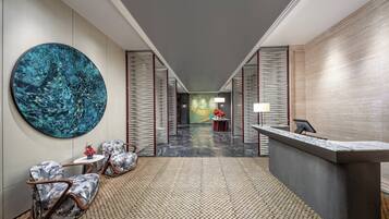 A modern lobby with a reception desk, seating area, and a large abstract painting on the wall.