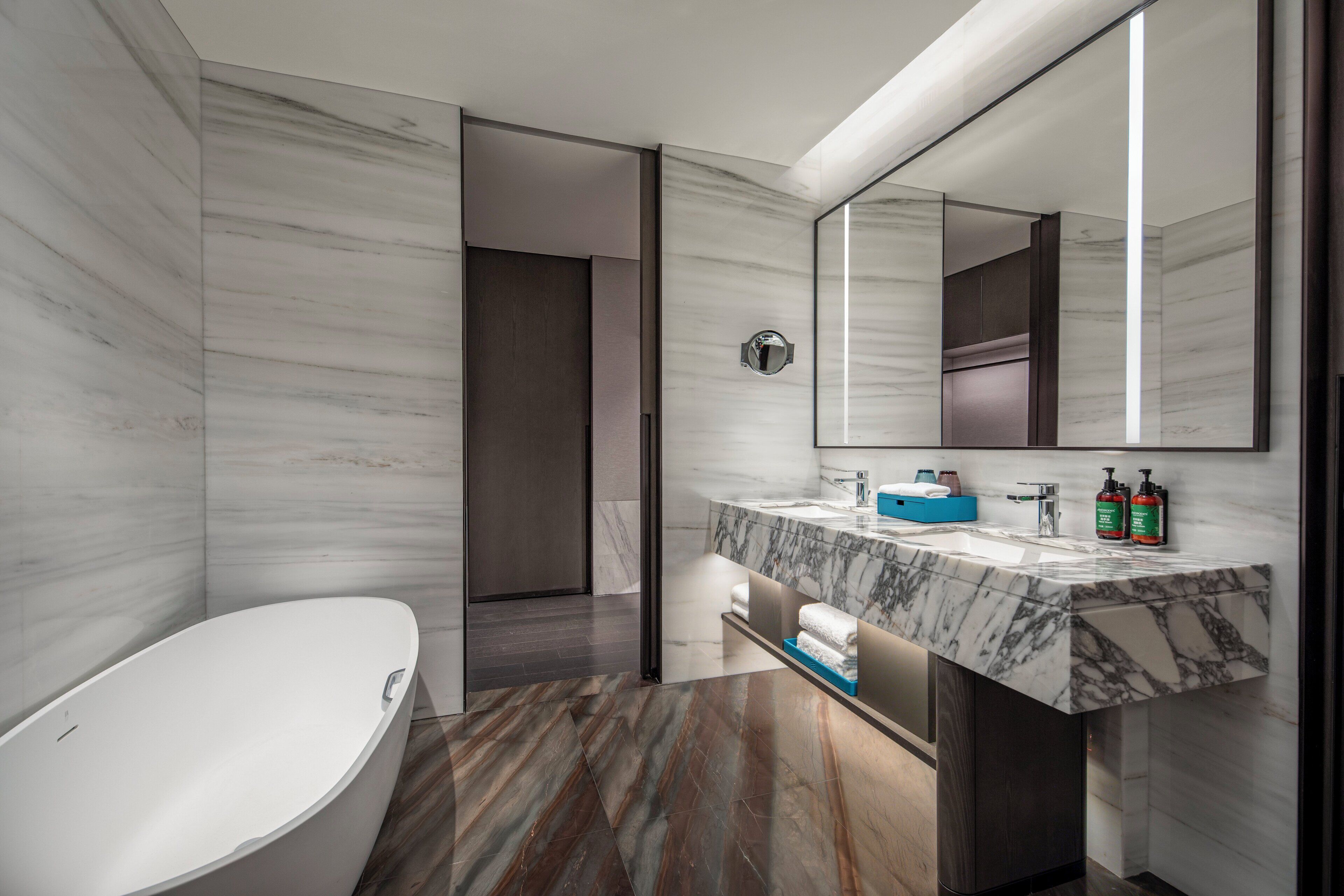 Une salle de bain moderne avec un meuble-lavabo en marbre, un grand miroir et une baignoire.