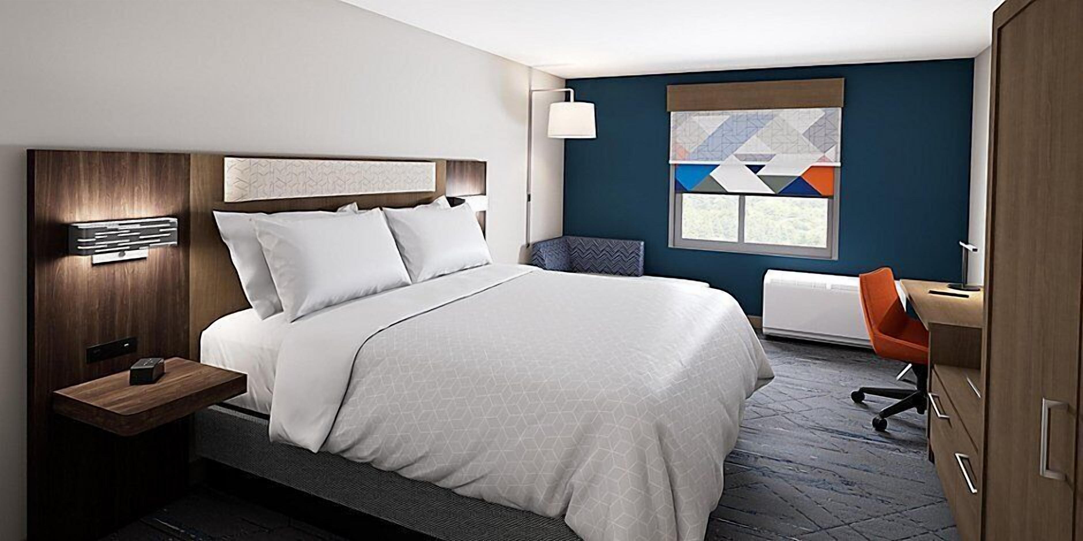 A modern hotel room with a large bed, a desk, and a chair.