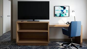 A hotel room with a flat-screen TV, a desk, a chair, and a wall-mounted abstract art piece.