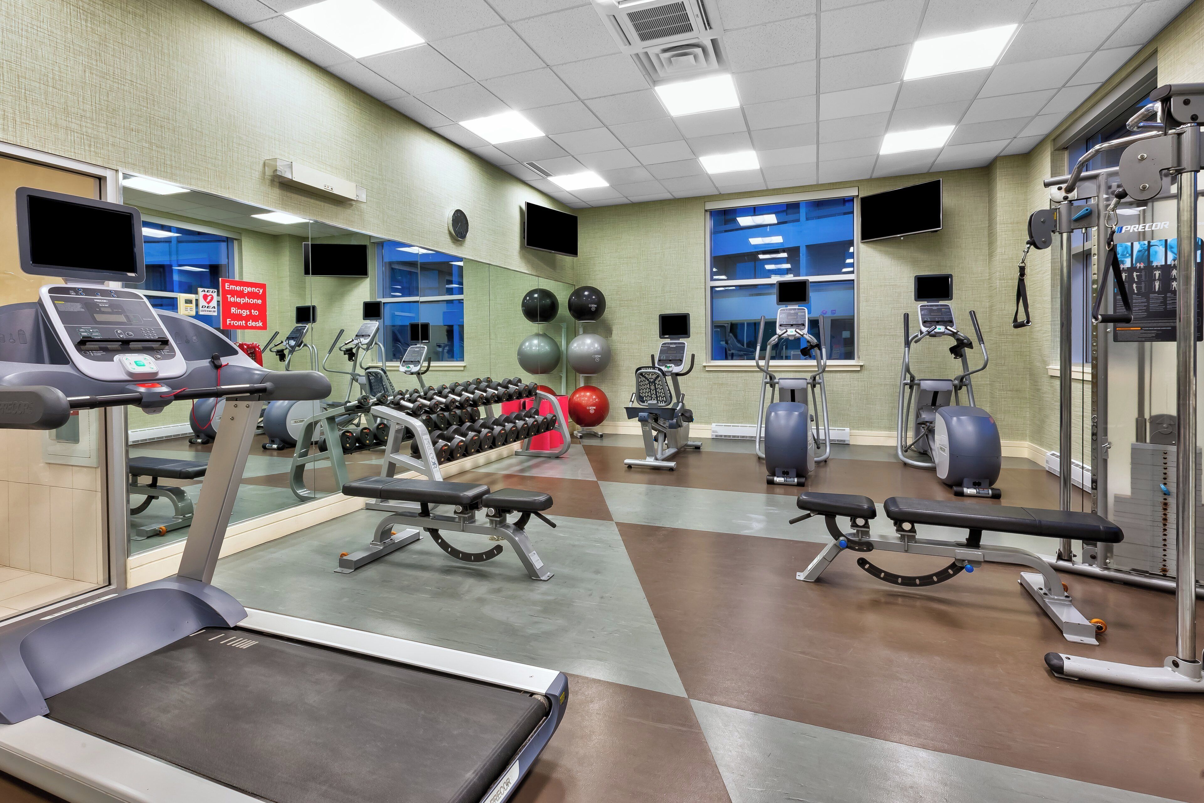 Een fitnessruimte met loopbanden, gewichtmachines en elastische fitnessballen.