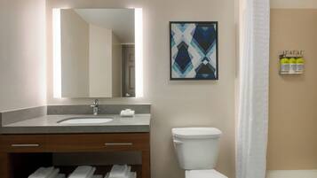 Un baño con lavabo, espejo, inodoro y cortina de ducha.