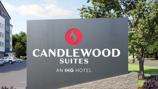 A sign for Candlewood Suites, an IHG hotel, with a logo, text, and surrounding landscaping. - Candlewood Suites St. John's Conference Centre by IHG (St. John's)