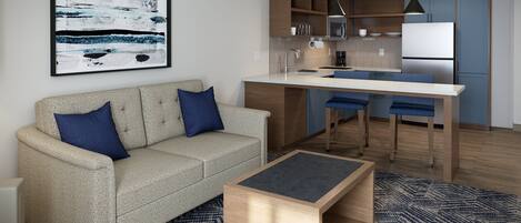 A modern living room with a sofa, a coffee table, and a kitchen area with a dining table and chairs.