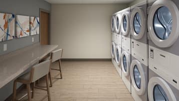 A laundry room with multiple washing machines, a counter, and bar stools.