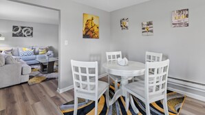 Una sala de estar moderna con comedor, que incluye un sofá, una mesa de centro y una mesa de comedor con sillas.