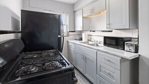 Cocina compacta equipada con estufa a gas, microondas, tostadora y refrigerador.