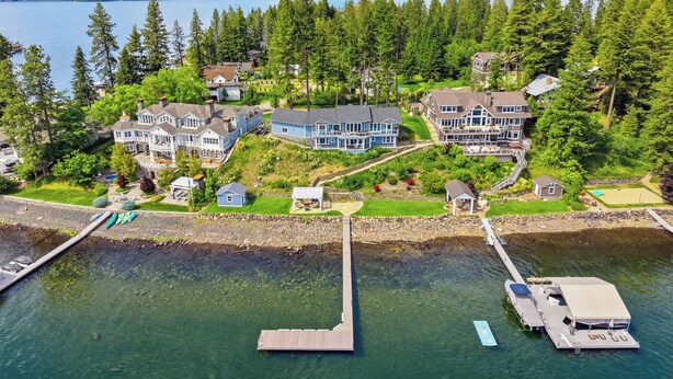 A waterfront property with multiple houses, a dock, and a boat. - Lakefront luxury with dock and views near Gozzer (Harrison)