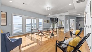 A spacious room with a large table, two chairs, and a view of the sea. - Lakefront luxury with dock and views near Gozzer (Harrison)
