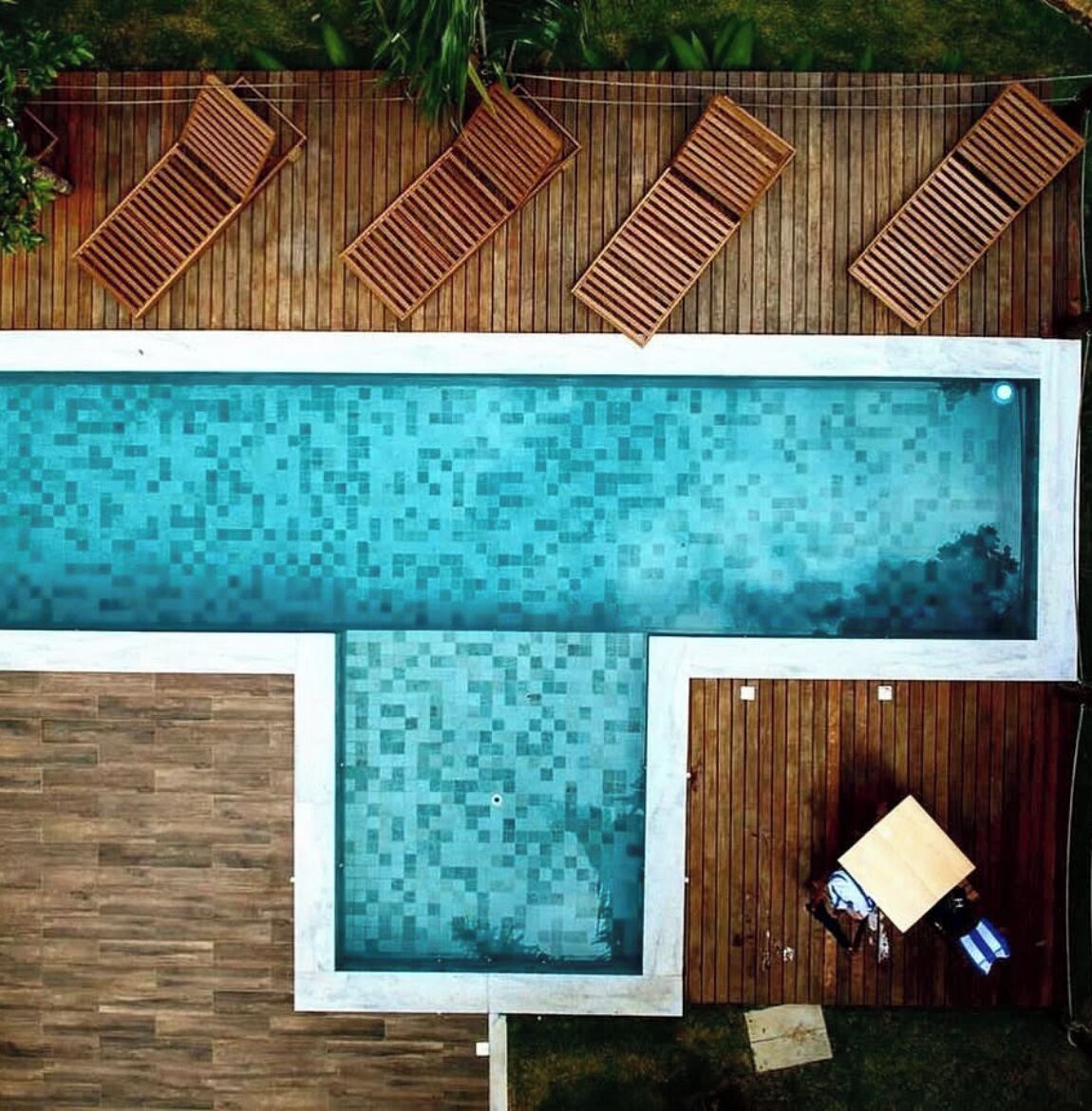 Una piscina rectangular con un borde de madera alrededor.