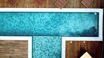 Una piscina rectangular con un borde de madera alrededor.