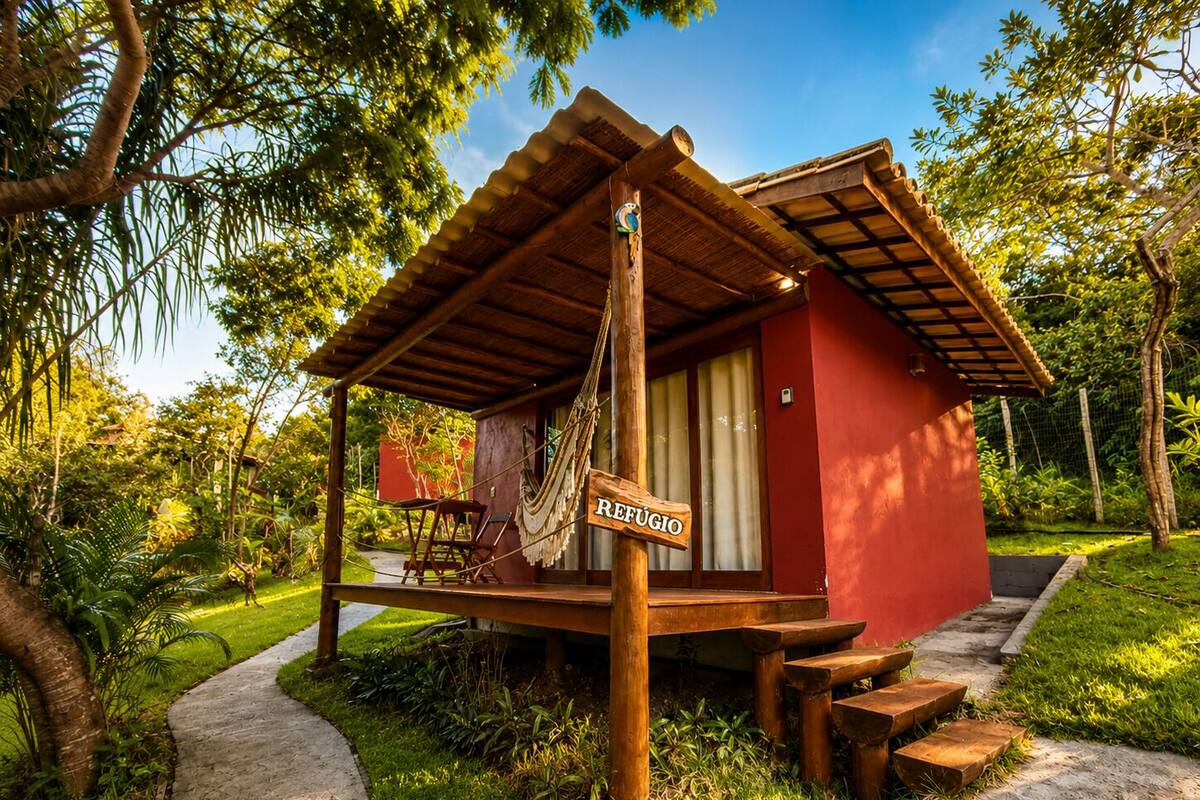 A small wooden structure with a sign reading 'REFUGIO' in a lush garden setting.