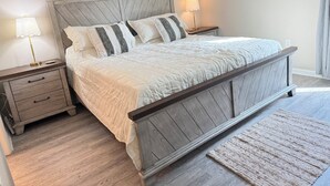 Ein Schlafzimmer mit einem hölzernen Bettgestell, zwei Nachttischen mit Lampen, einer Schublade und einem Teppich mit Struktur auf dem Boden.