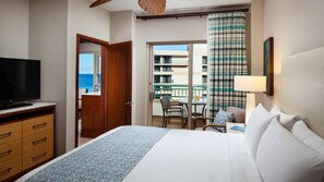 Habitació d'hotel amb llit, televisió, escriptori amb cadira i balcó amb vista al mar.
