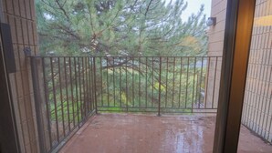 A balcony with a metal railing, a view of a tree, and a brick wall. - 306- Lava Hot Springs Resort Family Vacation Kitchen, 2 bathroom, condominium. (Lava Hot Springs)