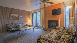 A living room with a sofa, a coffee table, a fireplace, a television, and a window with curtains. - 306- Lava Hot Springs Resort Family Vacation Kitchen, 2 bathroom, condominium. (Lava Hot Springs)