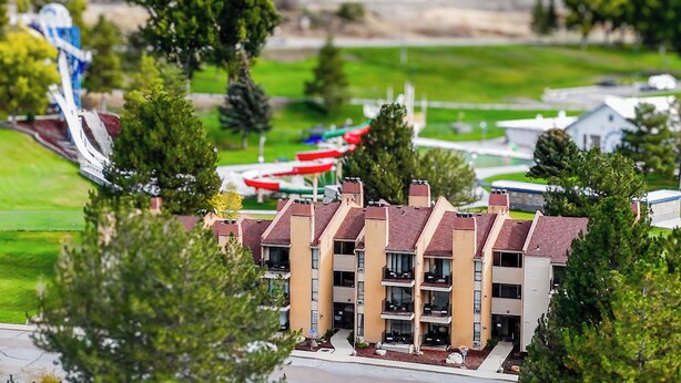 A model of a multi-story building with a flat roof, surrounded by greenery and a small body of water with boats. - 306- Lava Hot Springs Resort Family Vacation Kitchen, 2 bathroom, condominium. (Lava Hot Springs)