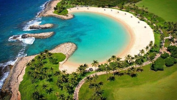 An aerial view of a beach resort with a curved shoreline, palm trees, and a clear blue sea. - Your Resort Home! Walk to Disney & Beach! (Kapolei)