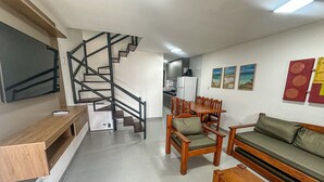 Un espace de vie moderne comprenant un escalier, des meubles en bois, un canapé et une table à manger.
