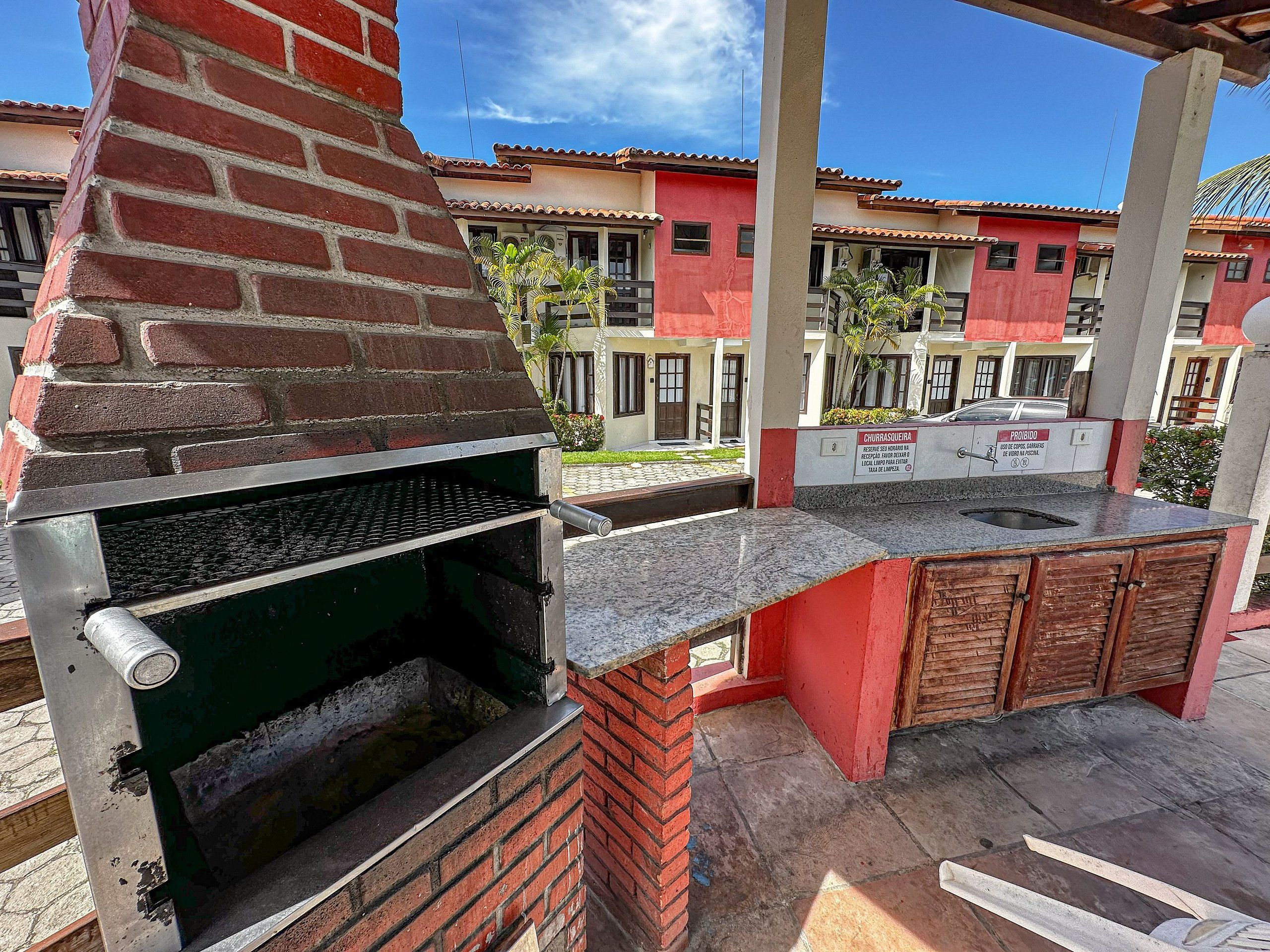 An outdoor kitchen area with a brick oven, a sink, and wooden cabinets.